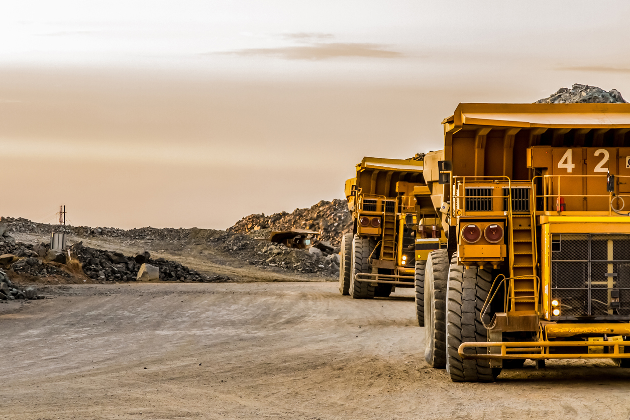 Large mining rock dump trucks transporting Platinum ore for processing