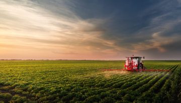 Tractor spraying pesticides on soy field with sprayer at spring